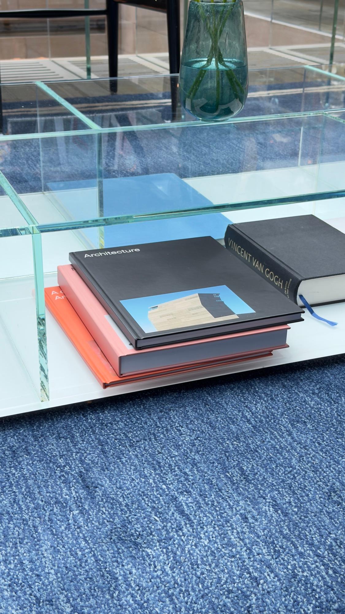 Three foto foto photo books stacked on a glass table, the top one titled Architecture