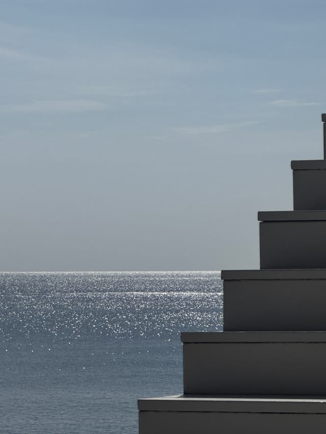 Zonlicht dat glinstert op de zee naast lichte betonnen treden
